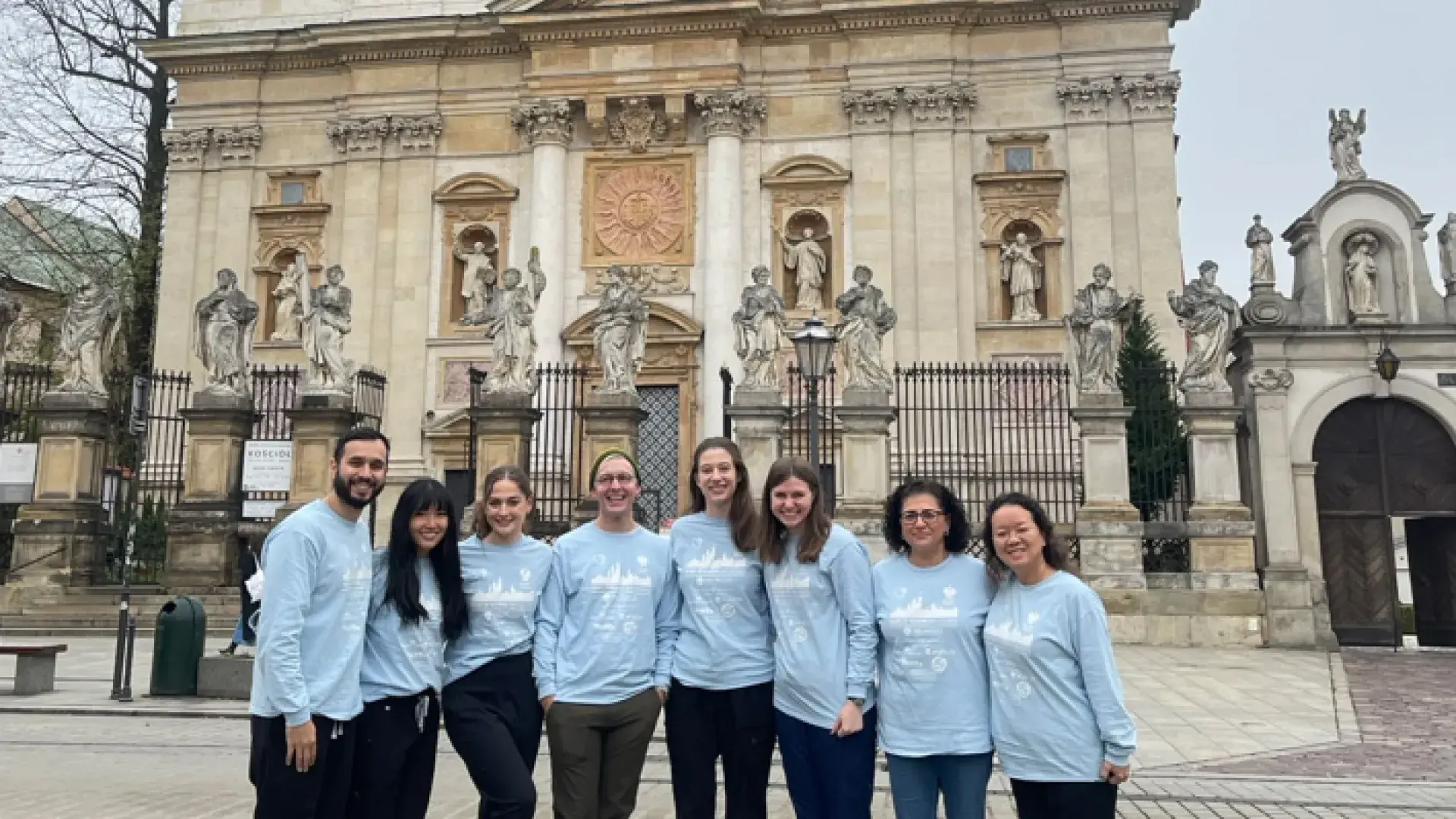 group of students and faculty stand outside fancy building