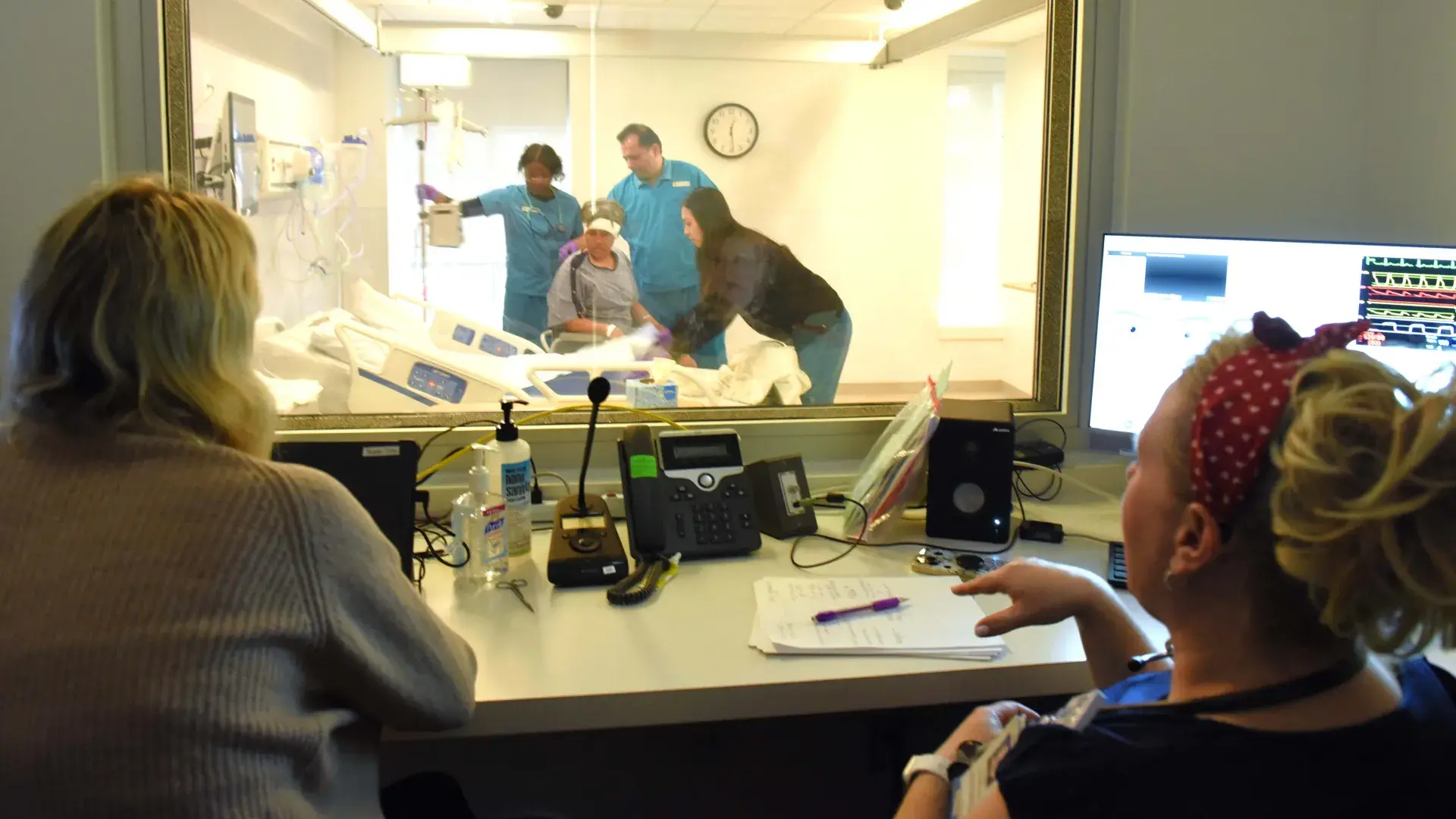 Nursing faculty watching  students work with a simulated participant in the IHP's Simulation Lab.