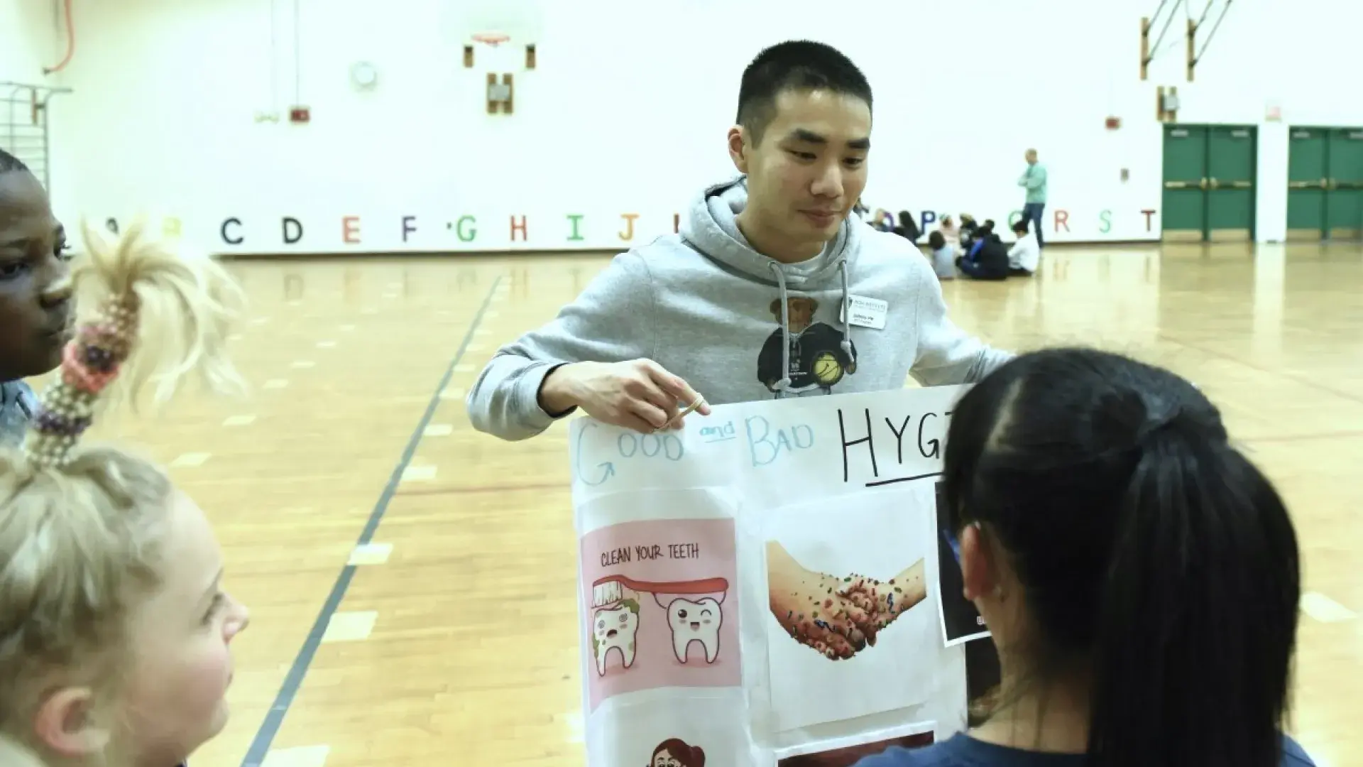 Man pointing out things in a poster to school children