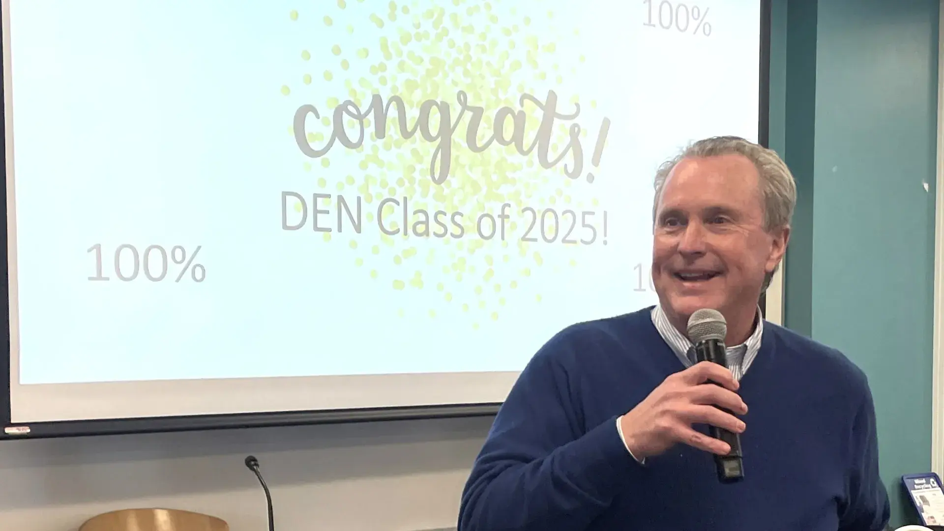 Man smiling, holding a mic