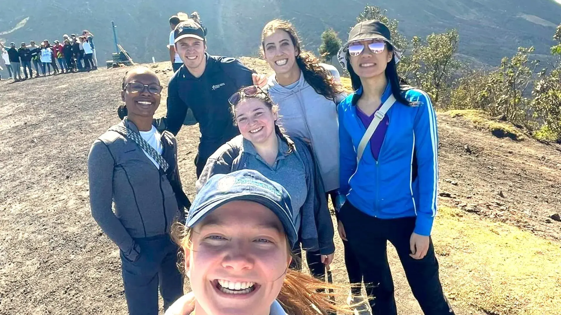 People pose for a selfie in front of a volcano