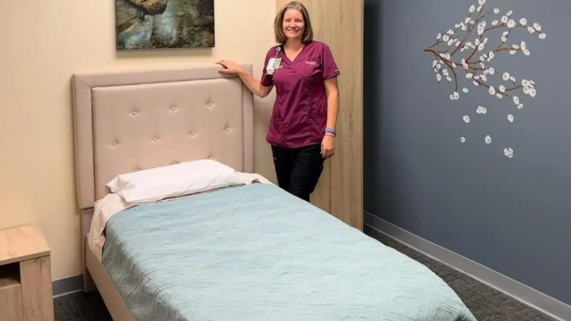 woman stands next to bed