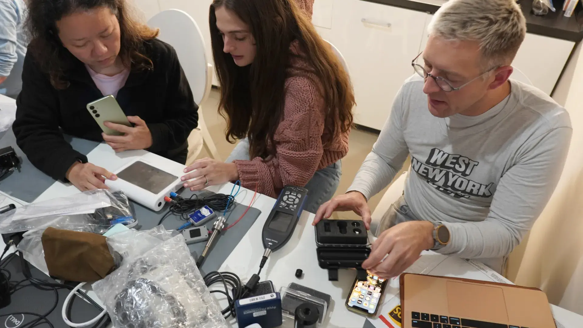 two women and man work with audiology equipment at table