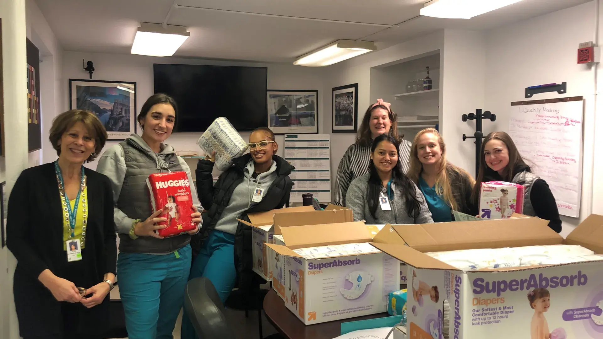 seven women stand with diapers in room