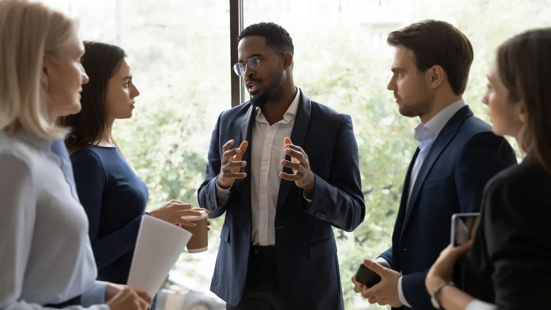 man in suit speaking to group of other professionally dressed people