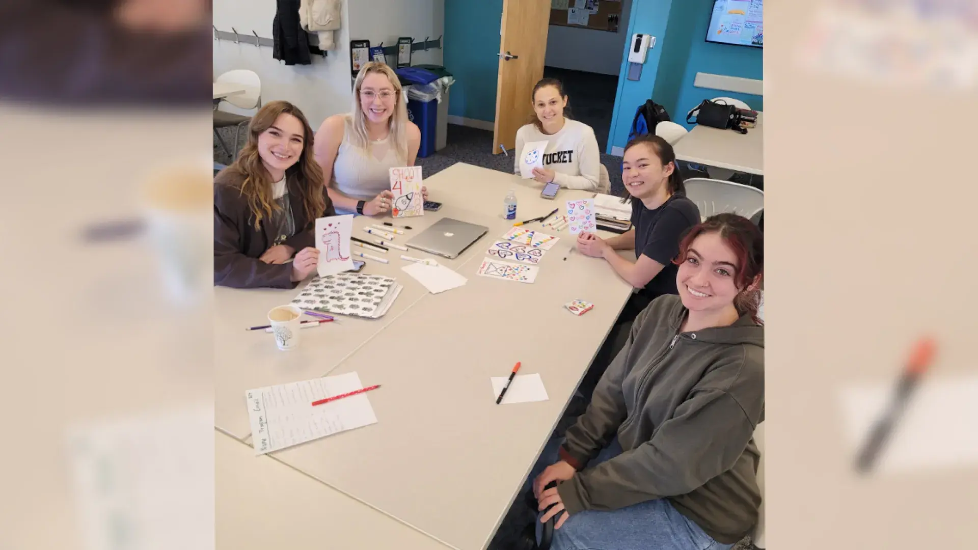 people sitting around a table smiling with cards and markers