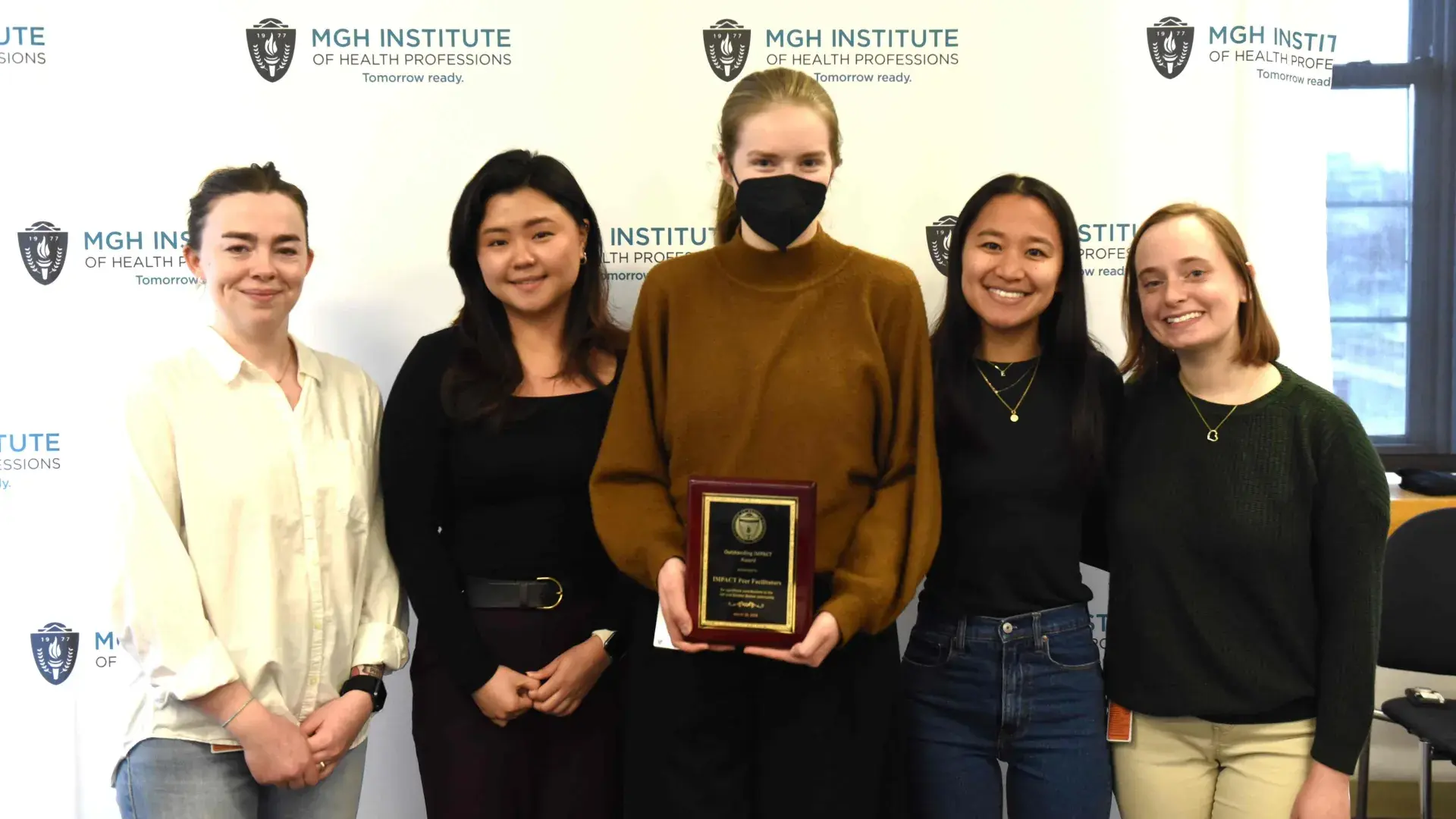 Five people smiling in front of a banner