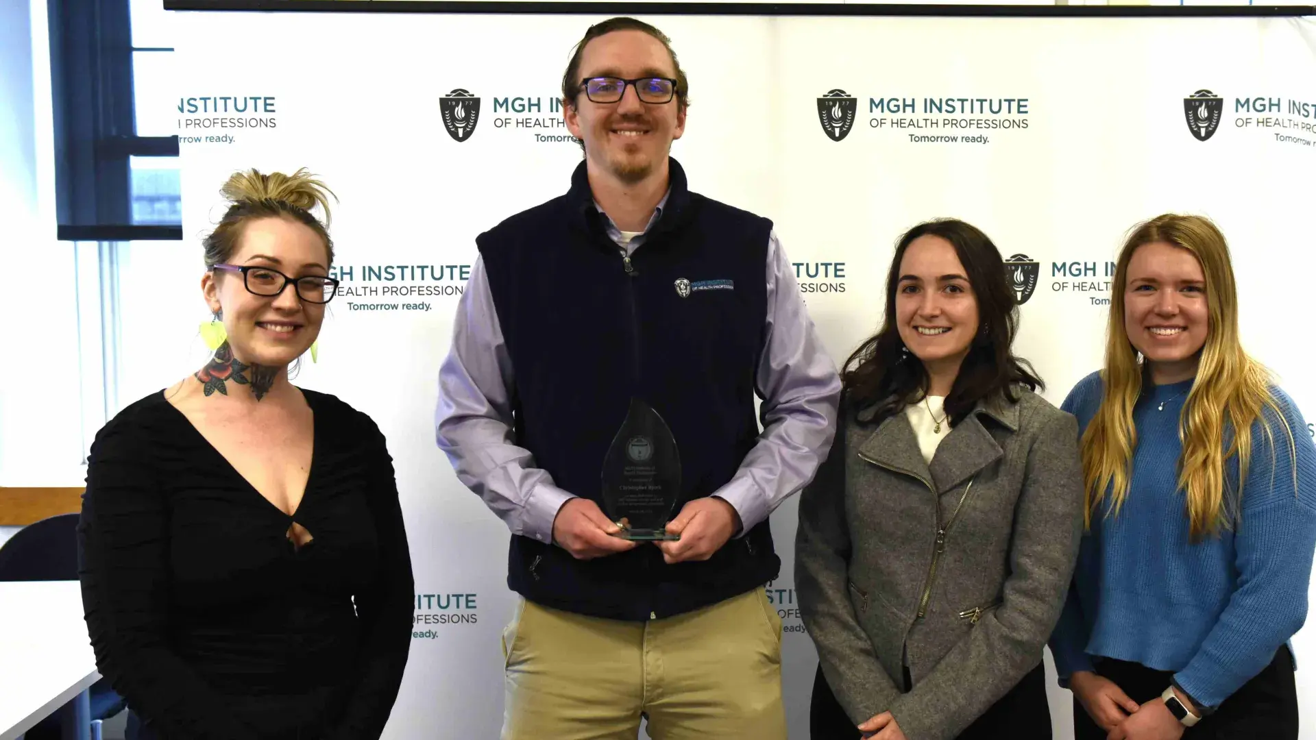 Four people smiling in front of a banner