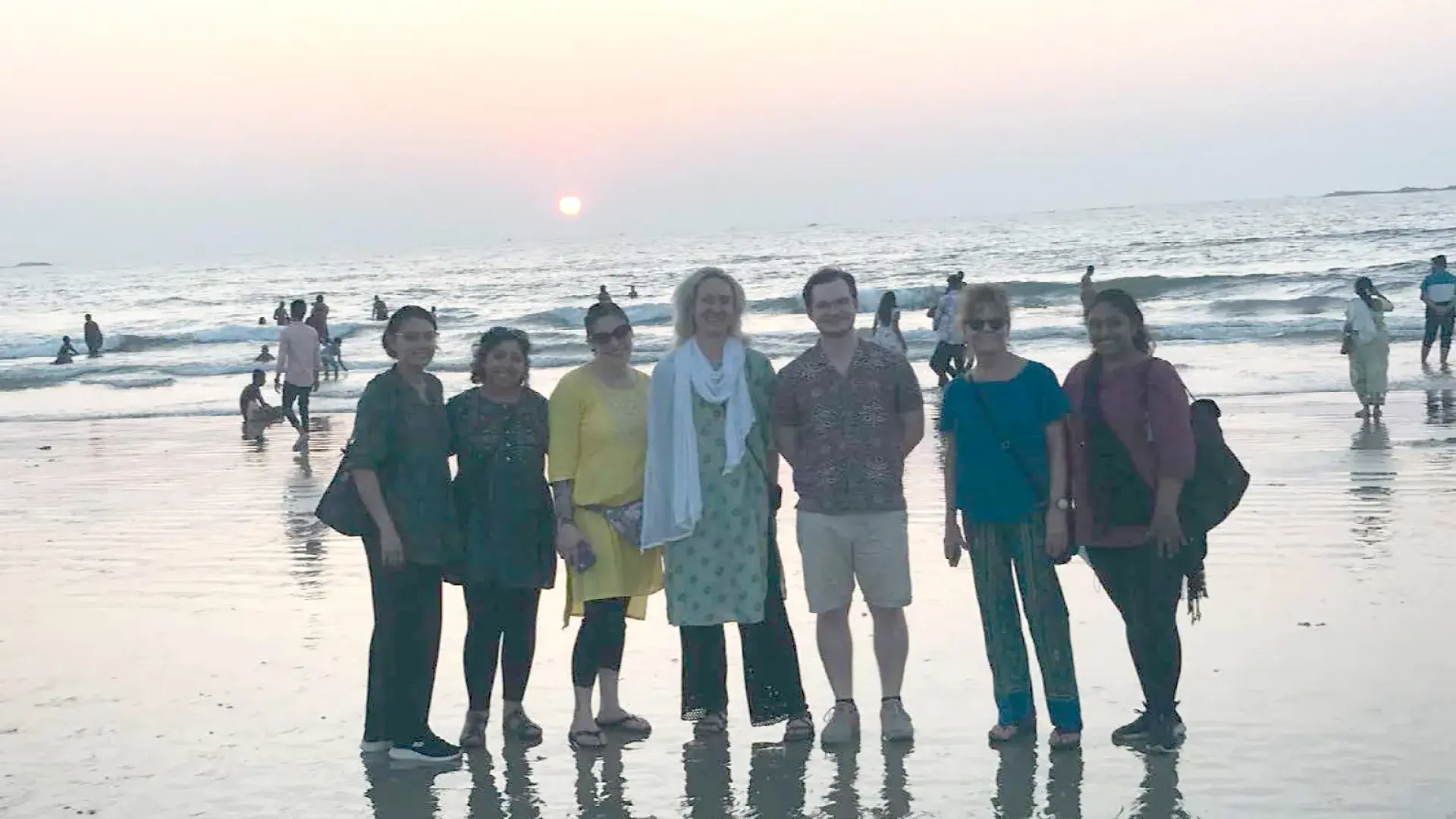 seven people stand on a beach