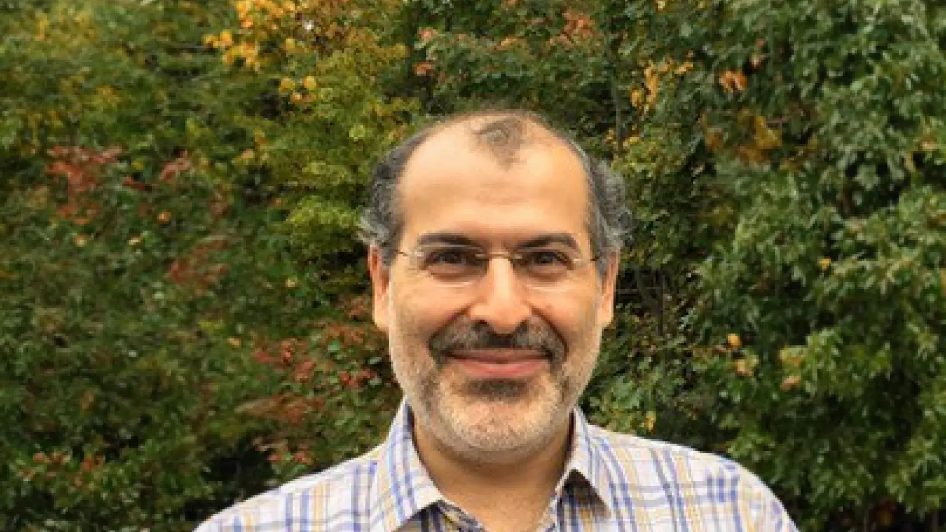 pedram stands in front of a grove of trees