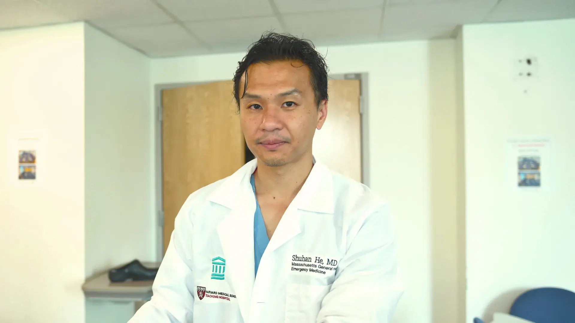shuhan stands at a computer in a clinical office and wears a white coat 