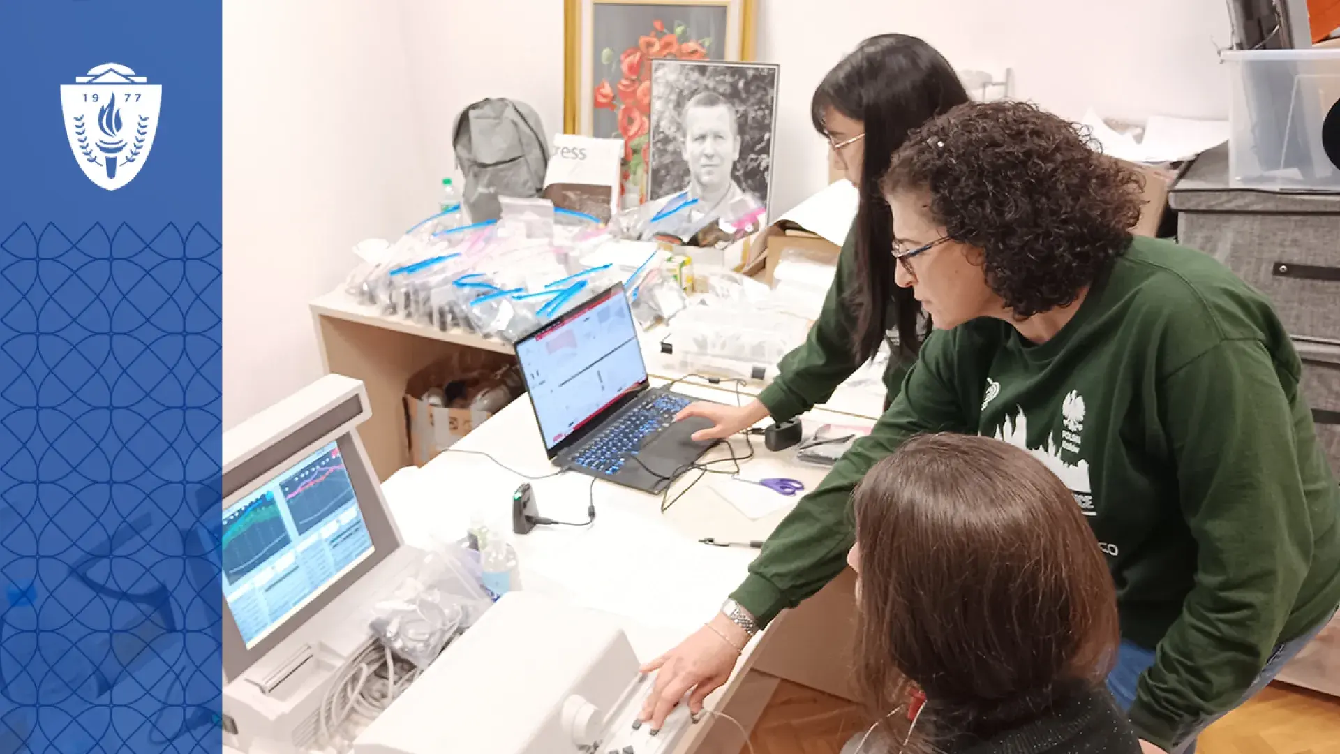 three people work at computers with various technology on the table