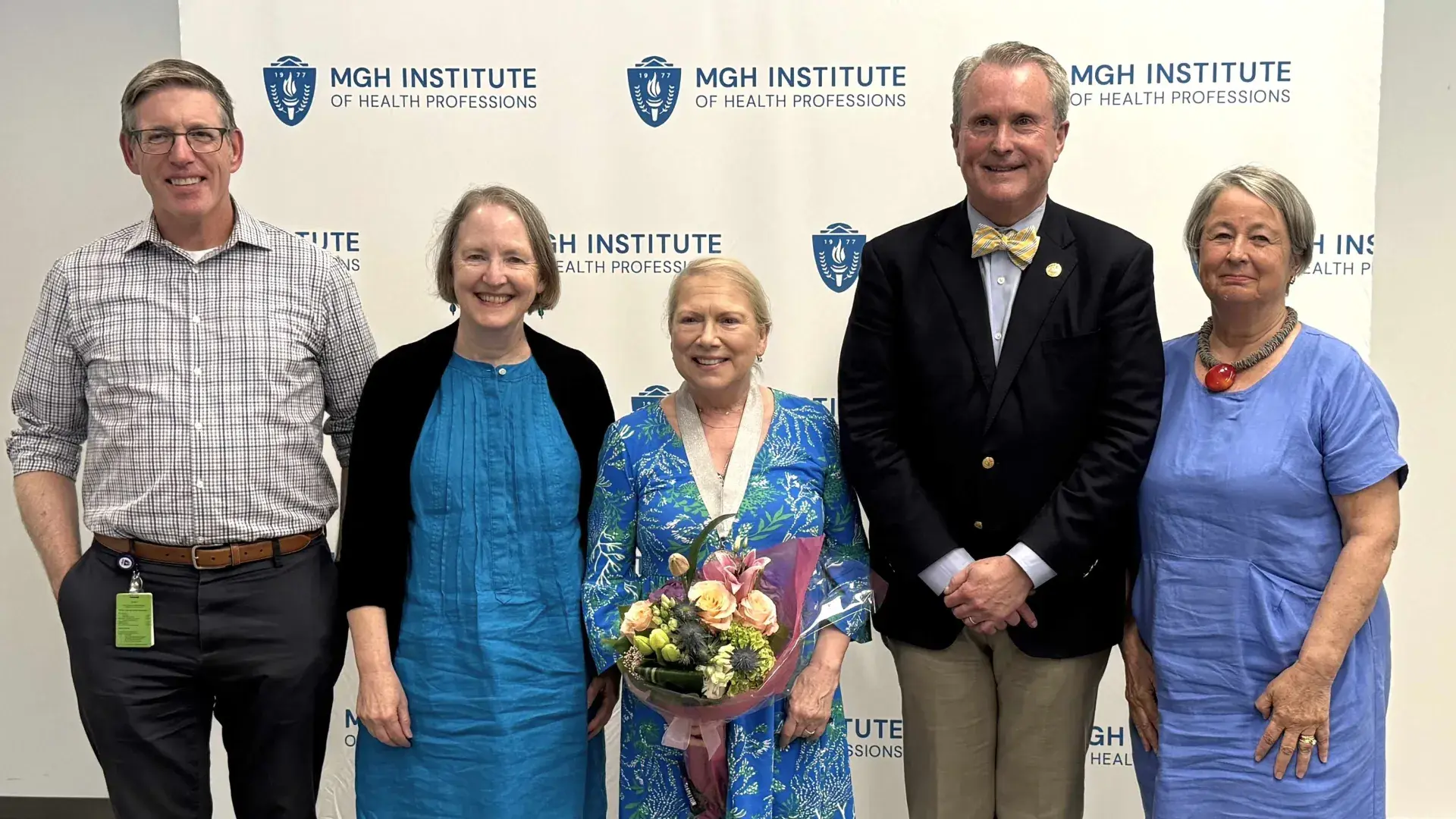 Five people standing in a row smiling