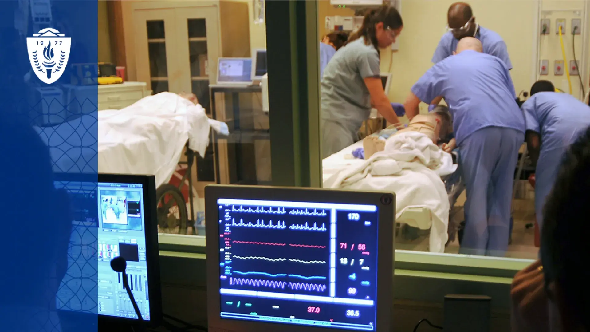 a computer screen with lines monitoring vitals like heartbeats is in front of a window where people in scrubs are working on a manikin in a hospital bed