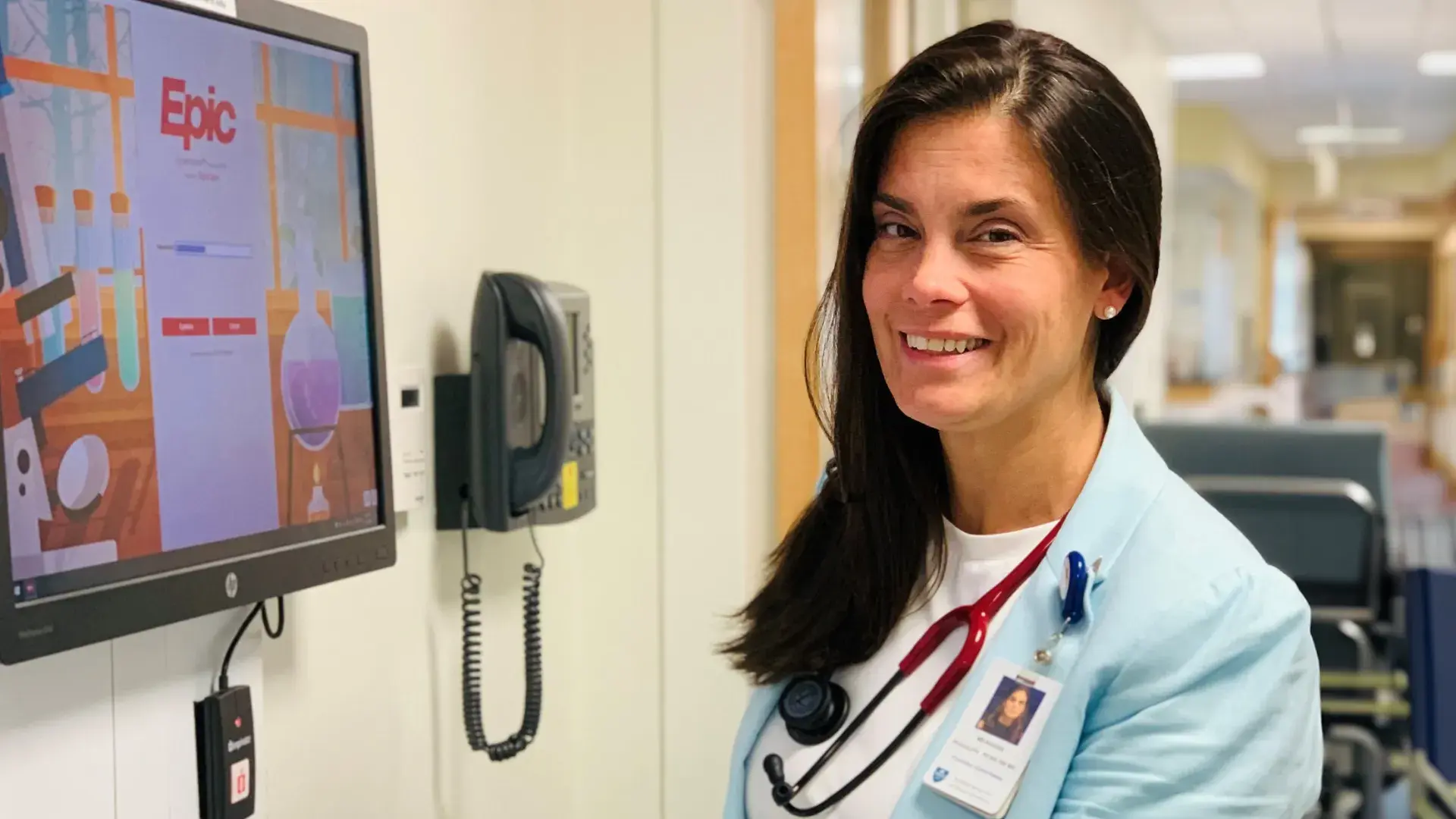 woman standing at a computer in a hospital hallway