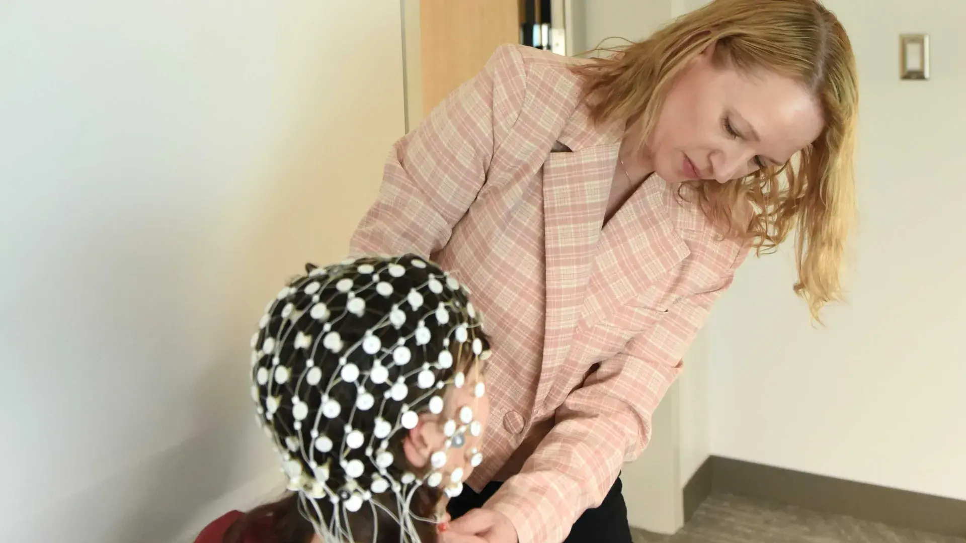 Woman fitting an EEG headset on a client