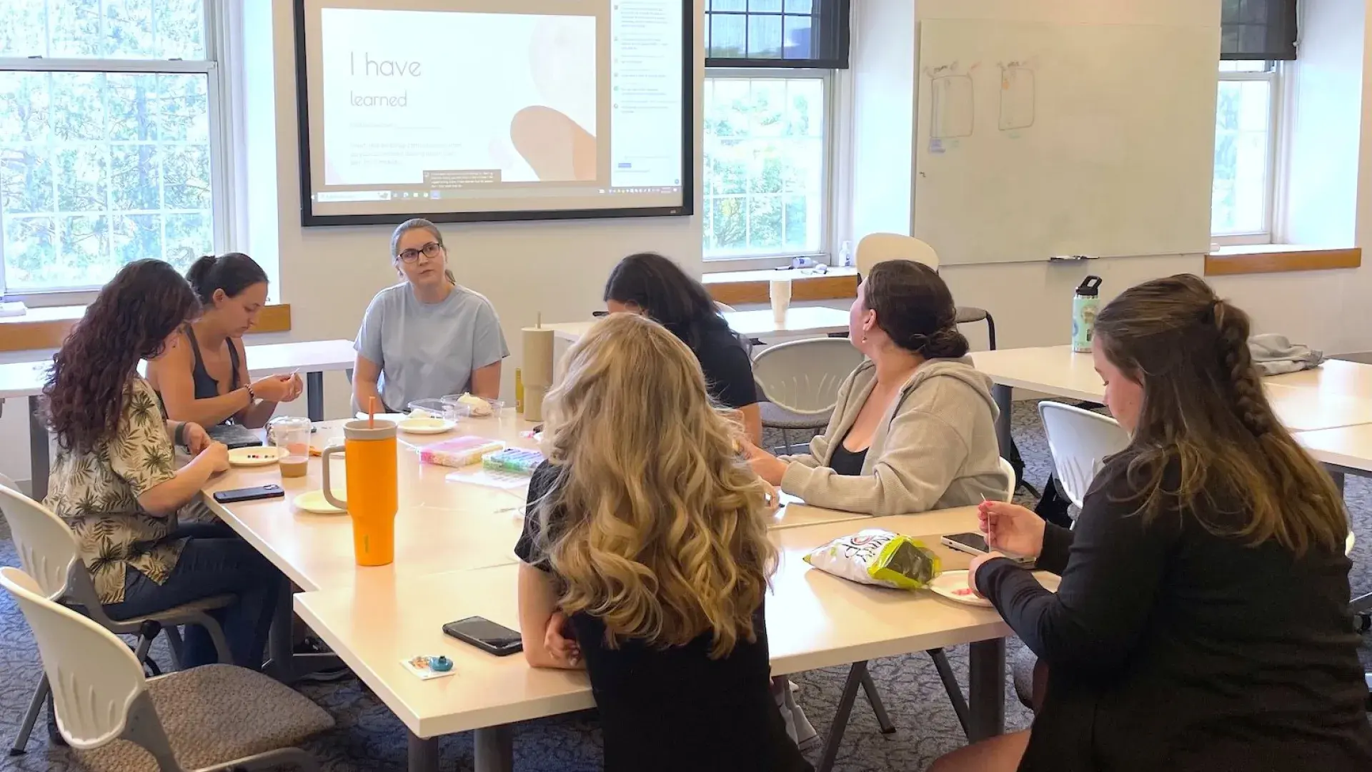 Students listening to a speaker, sitting at a table