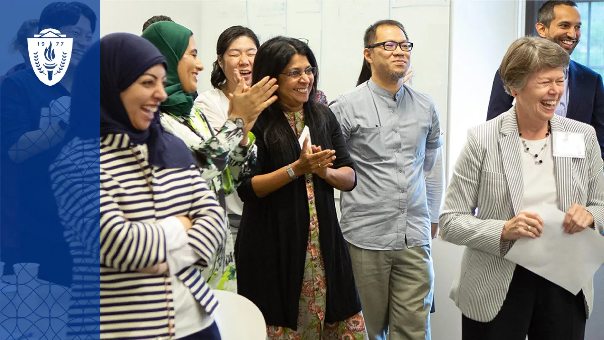 a mix of women and men of different ages and races stand in a group and smile