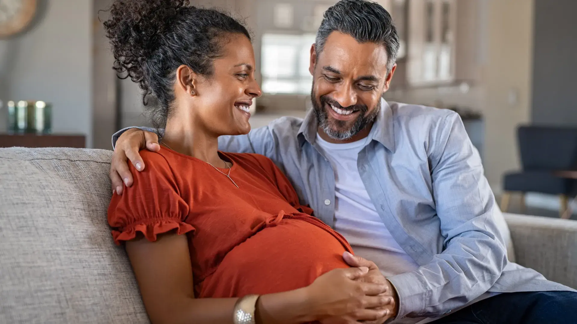 smiling man and pregnant woman on a couch