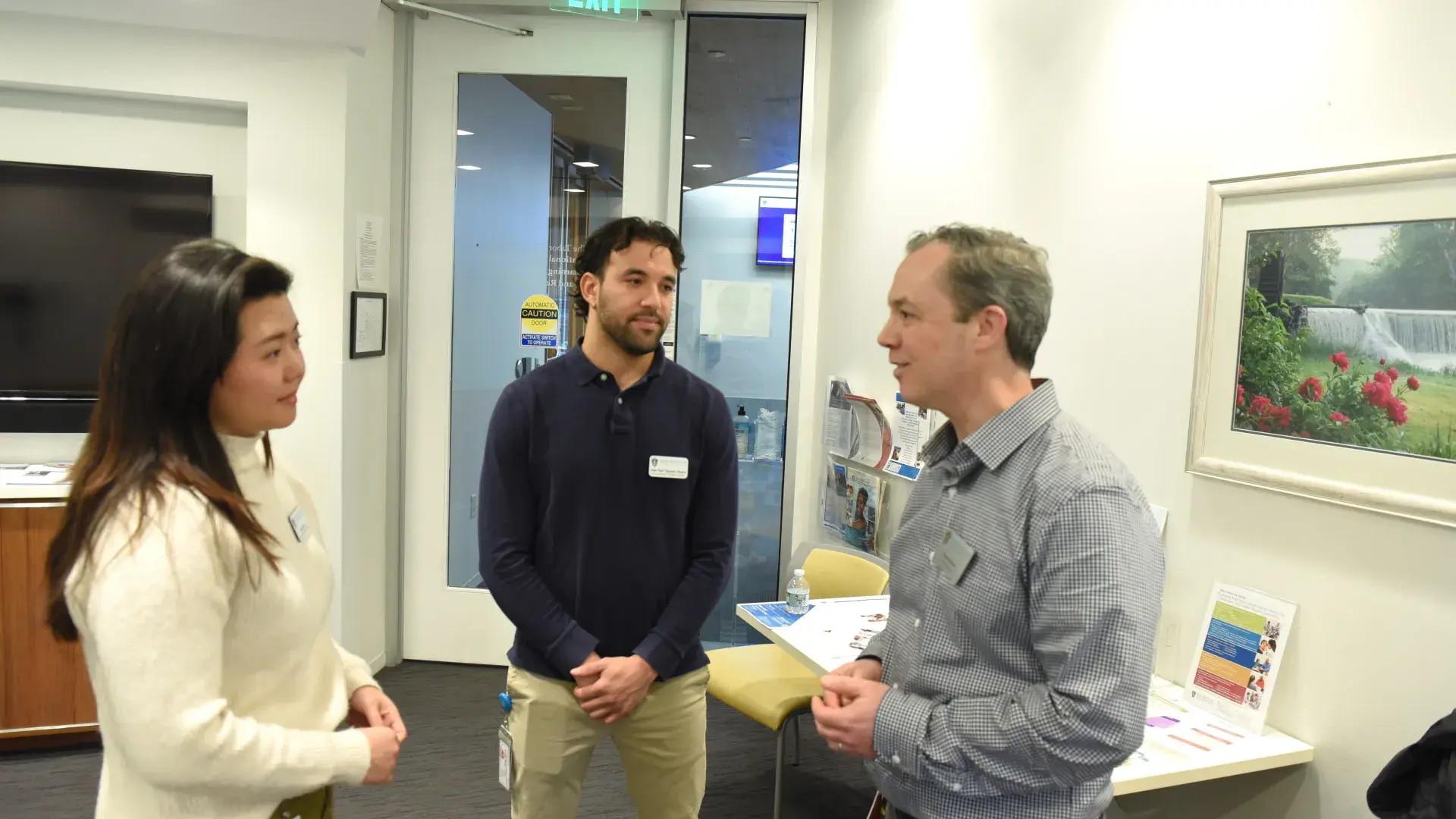 Three people facing each other talk in an office
