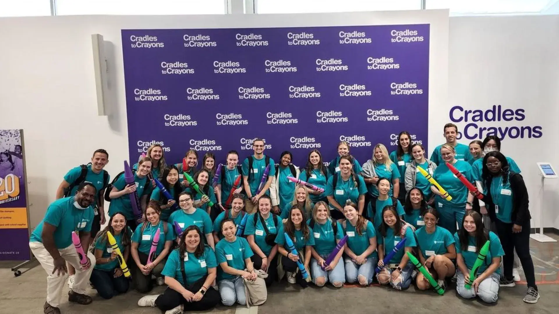 Students pose in front of a banner for Cradles to Crayons