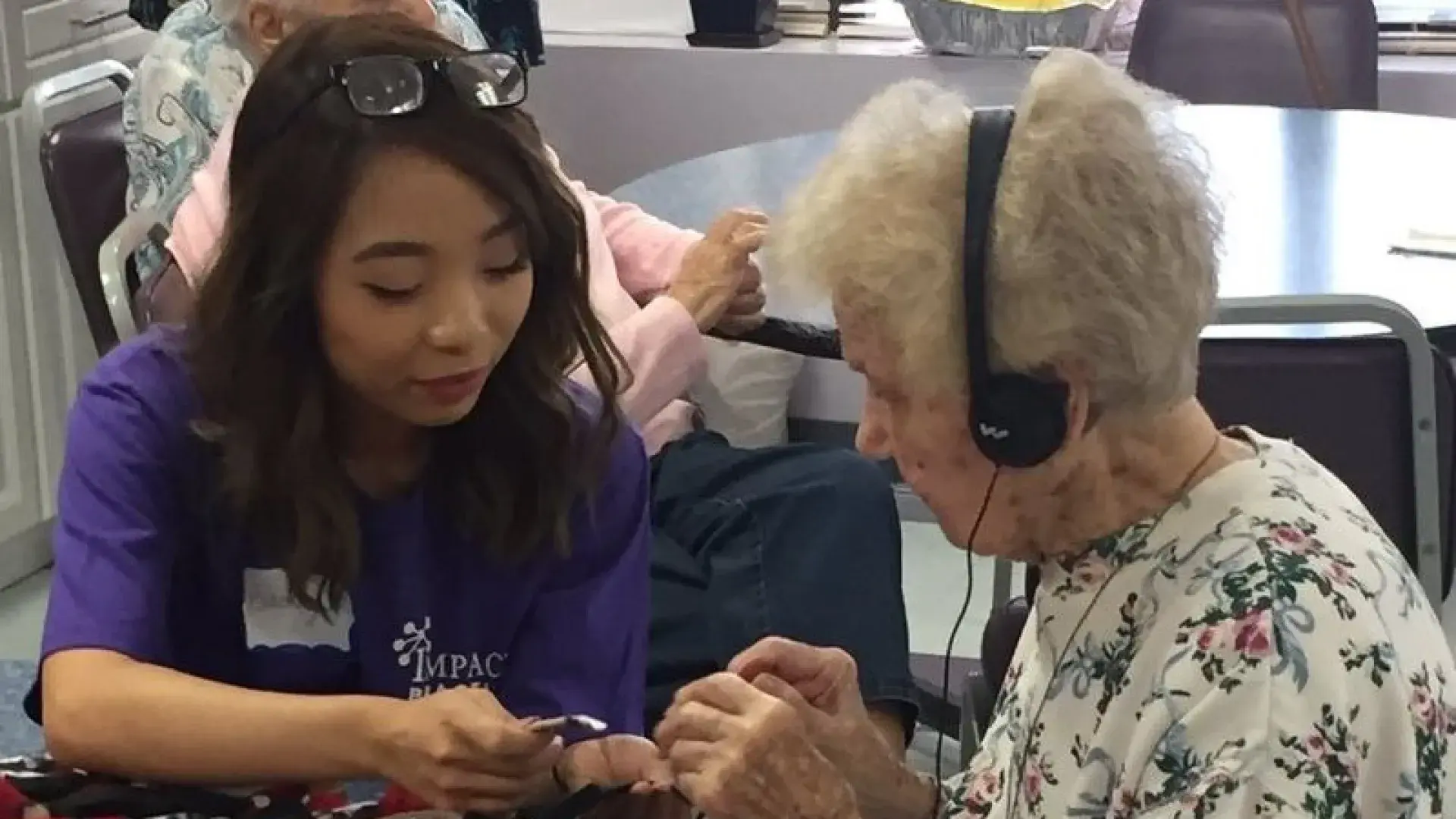 A younger woman helps and older woman make a blanket