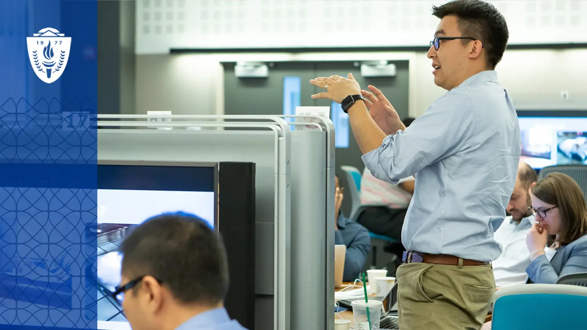 man gestures at front of classroom
