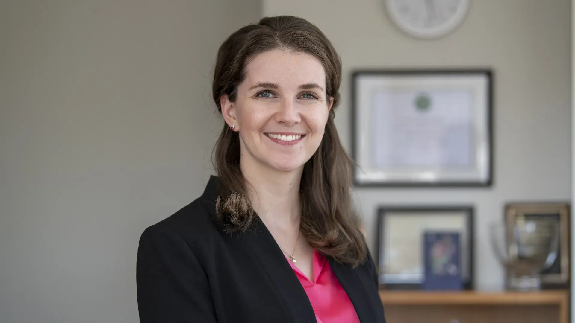 sarah wears a black blazer and hot pink shirt