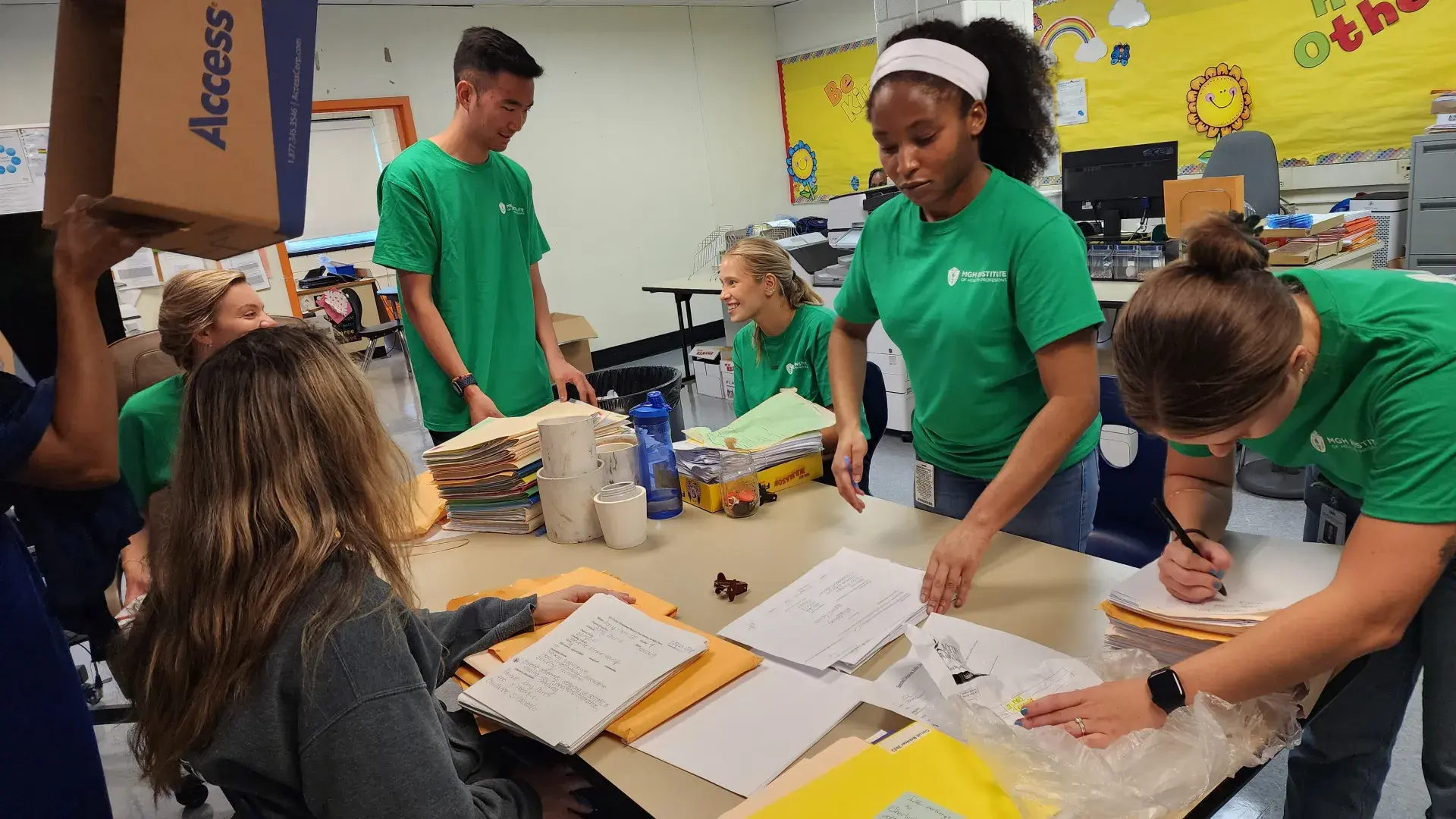 People work on paperwok while standing and sitting around a table