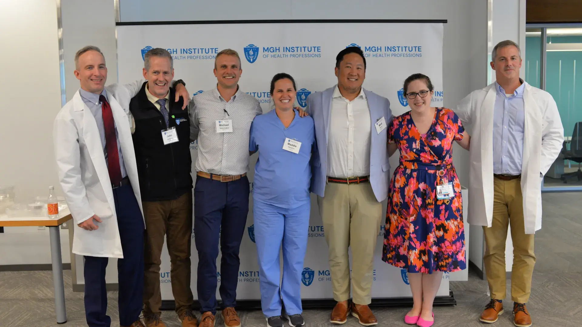 seven people stand in front of a backdrop. 