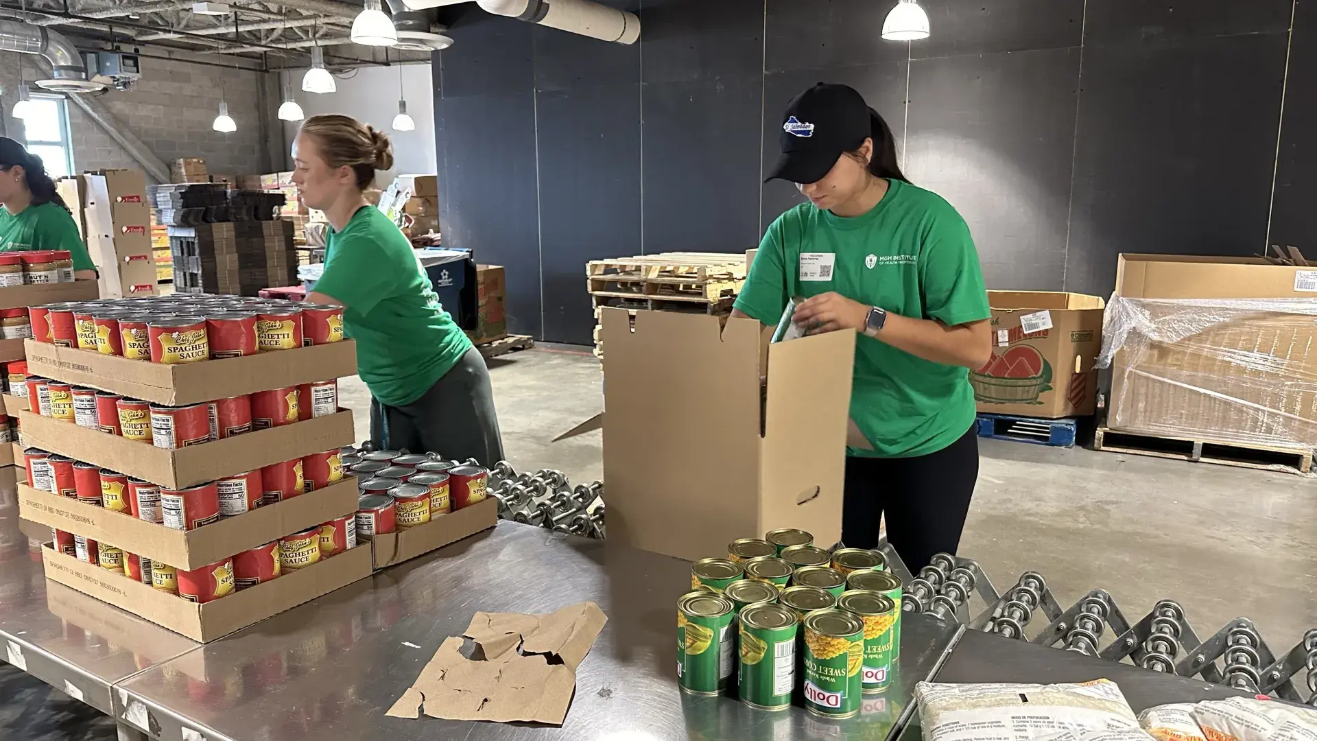 Two women put food in boxes 