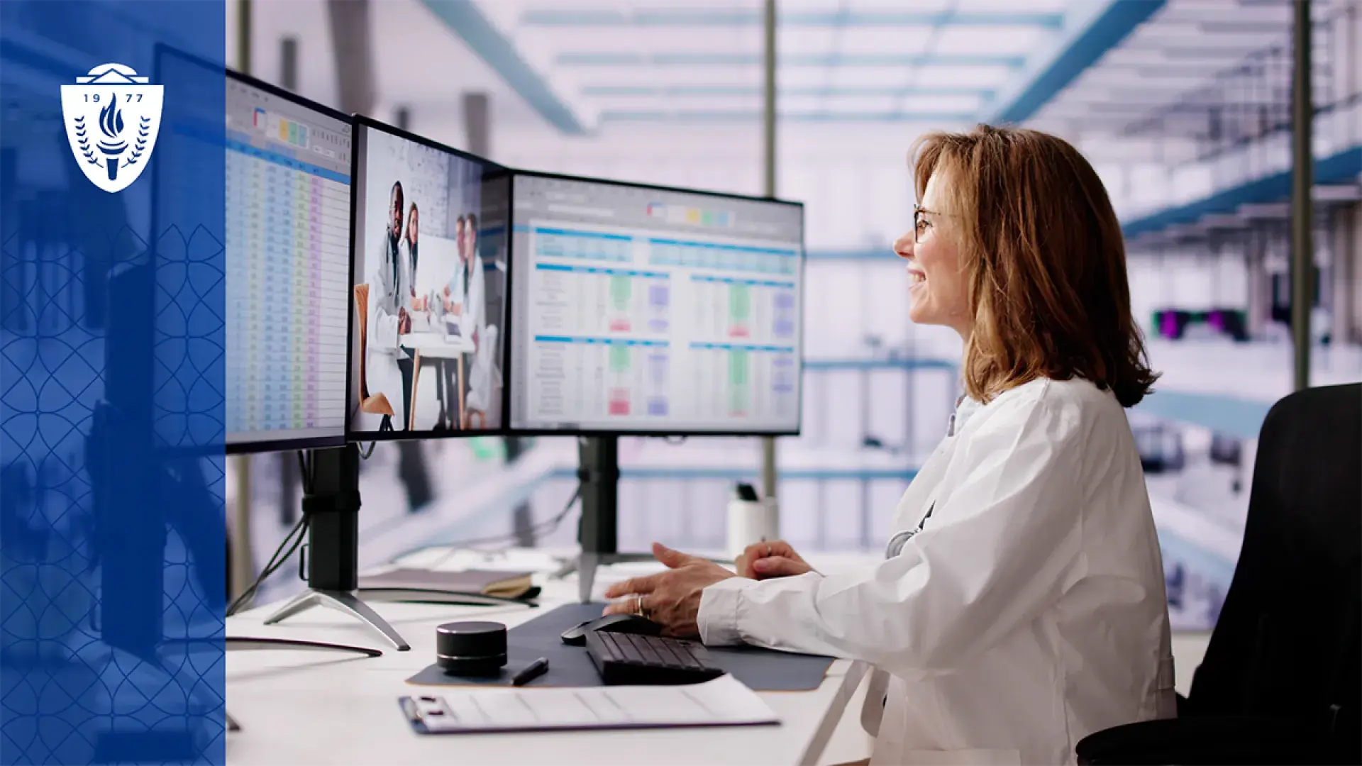 a woman in a white lab coat looks at data on three computer screens