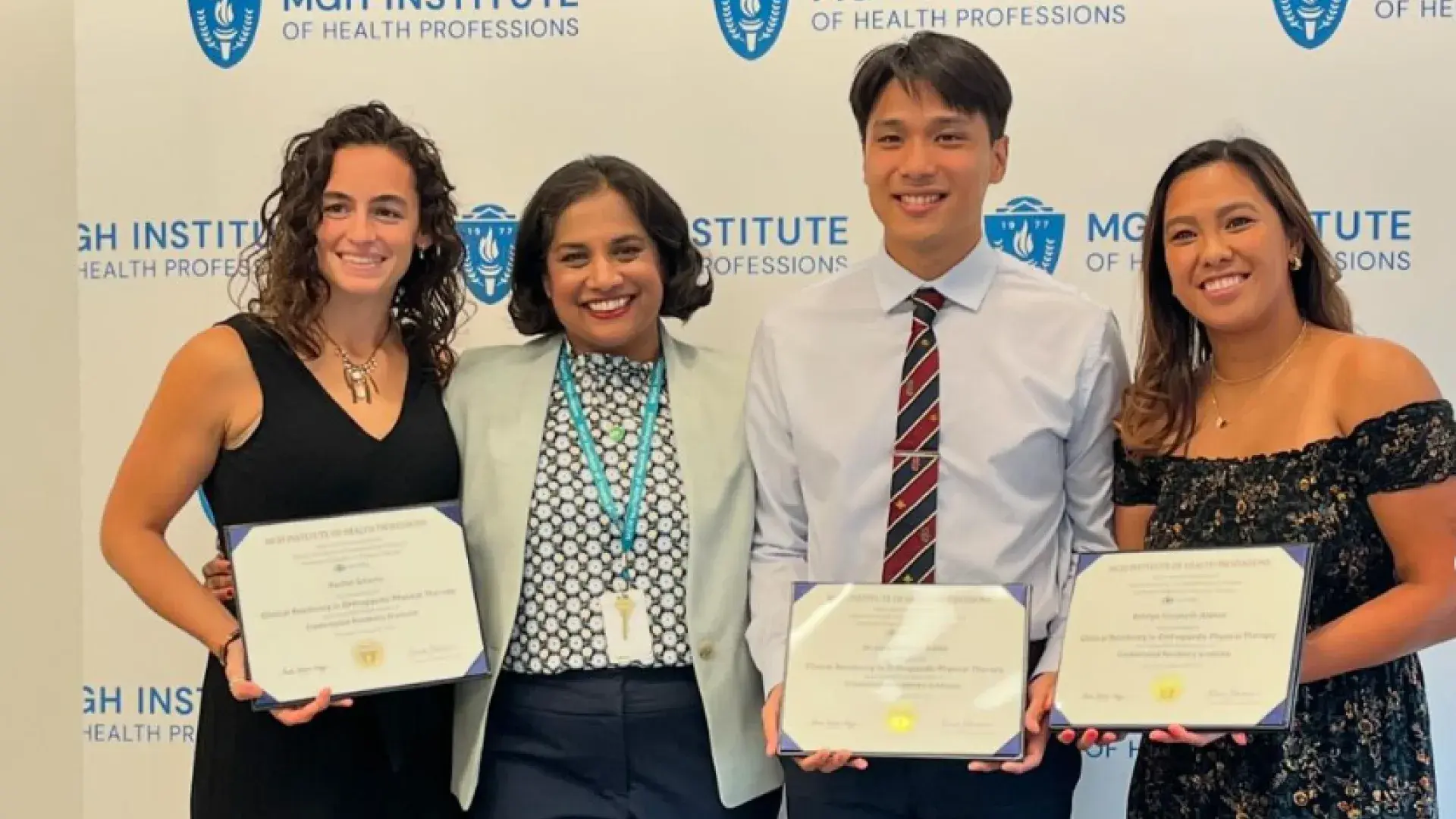 Four people pose in front of a backdrop holding certificates