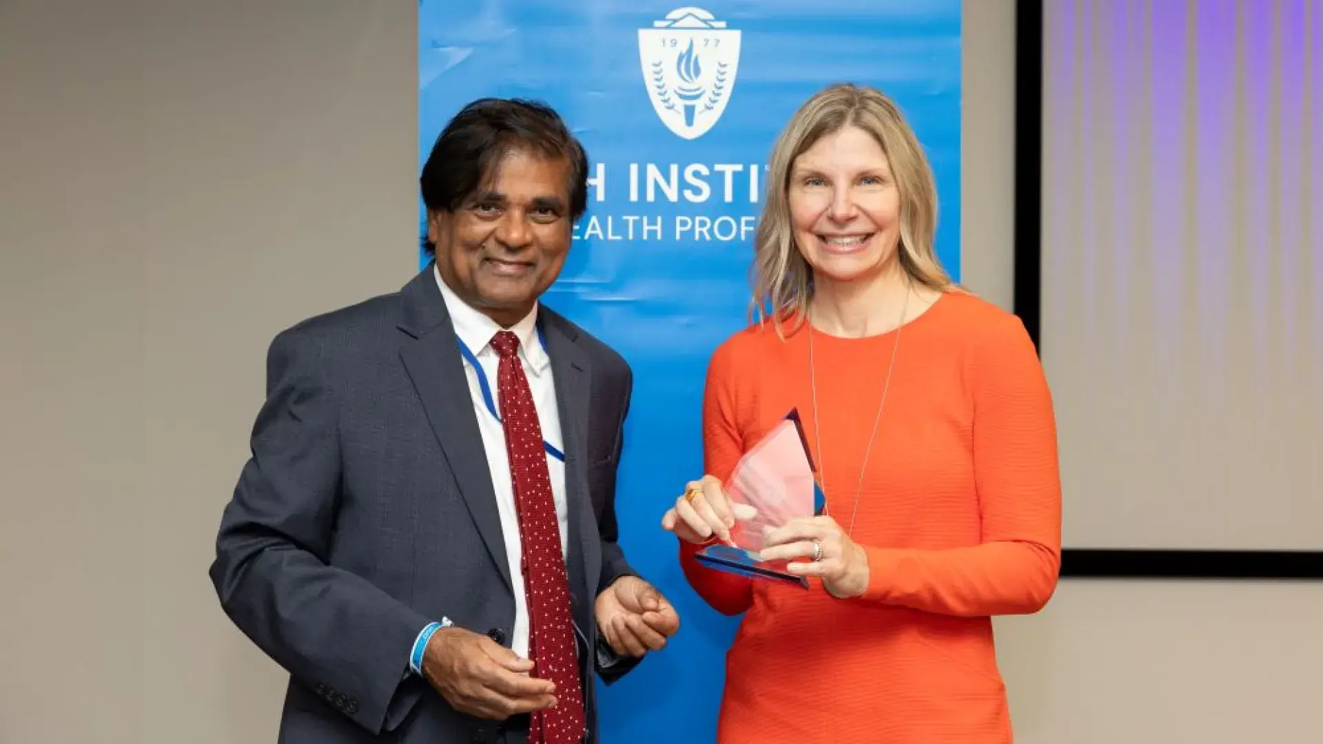 man and woman stand in front of MGH banner with award