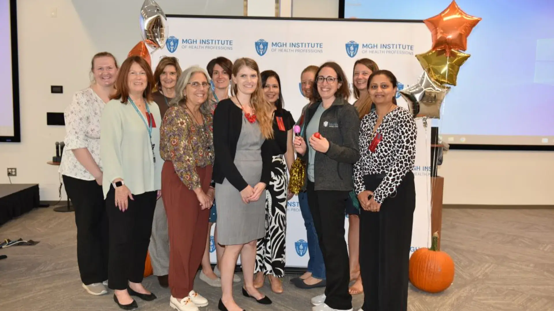 group stands in front of MGH banner