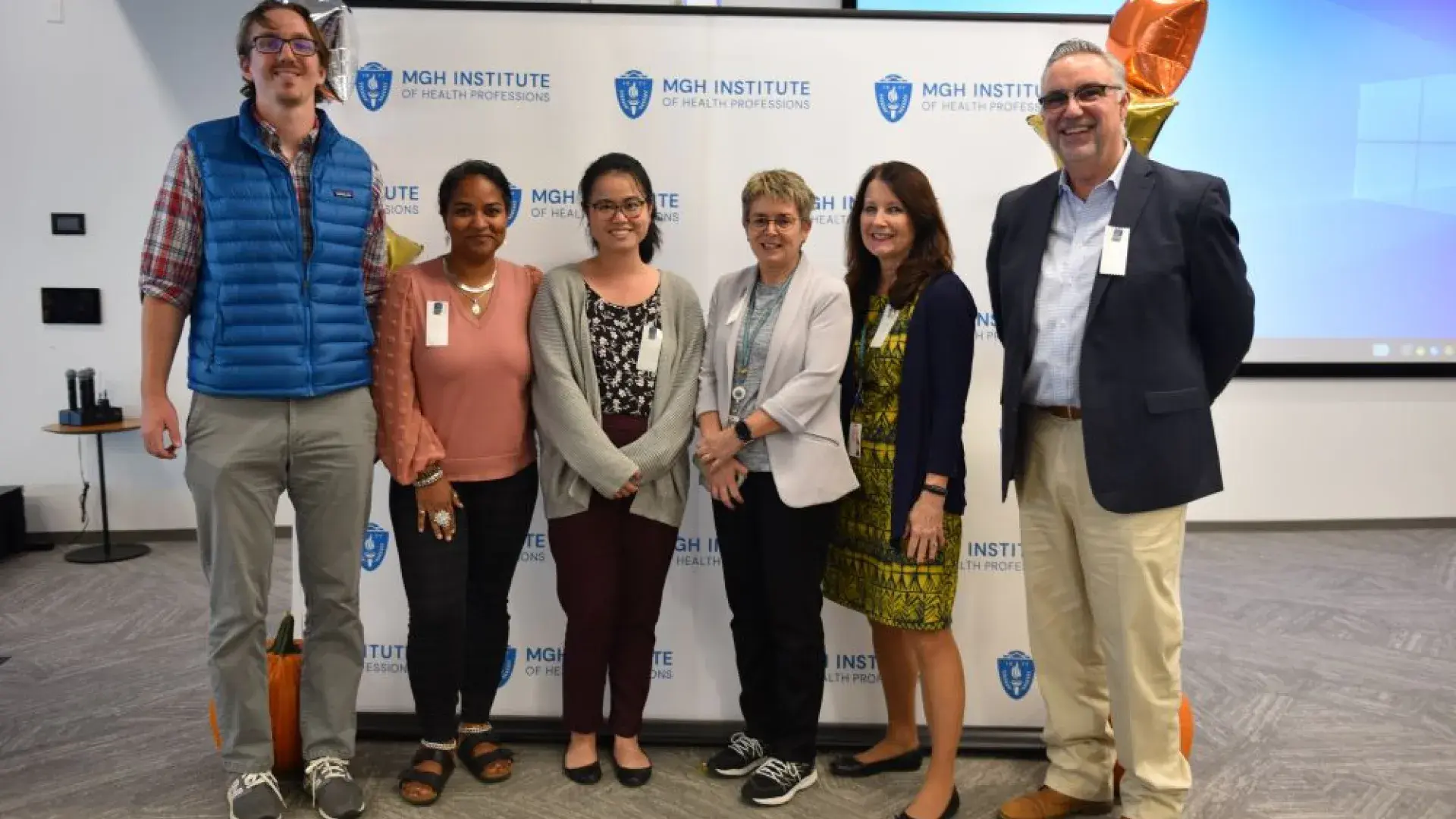 group stands in front of MGH banner