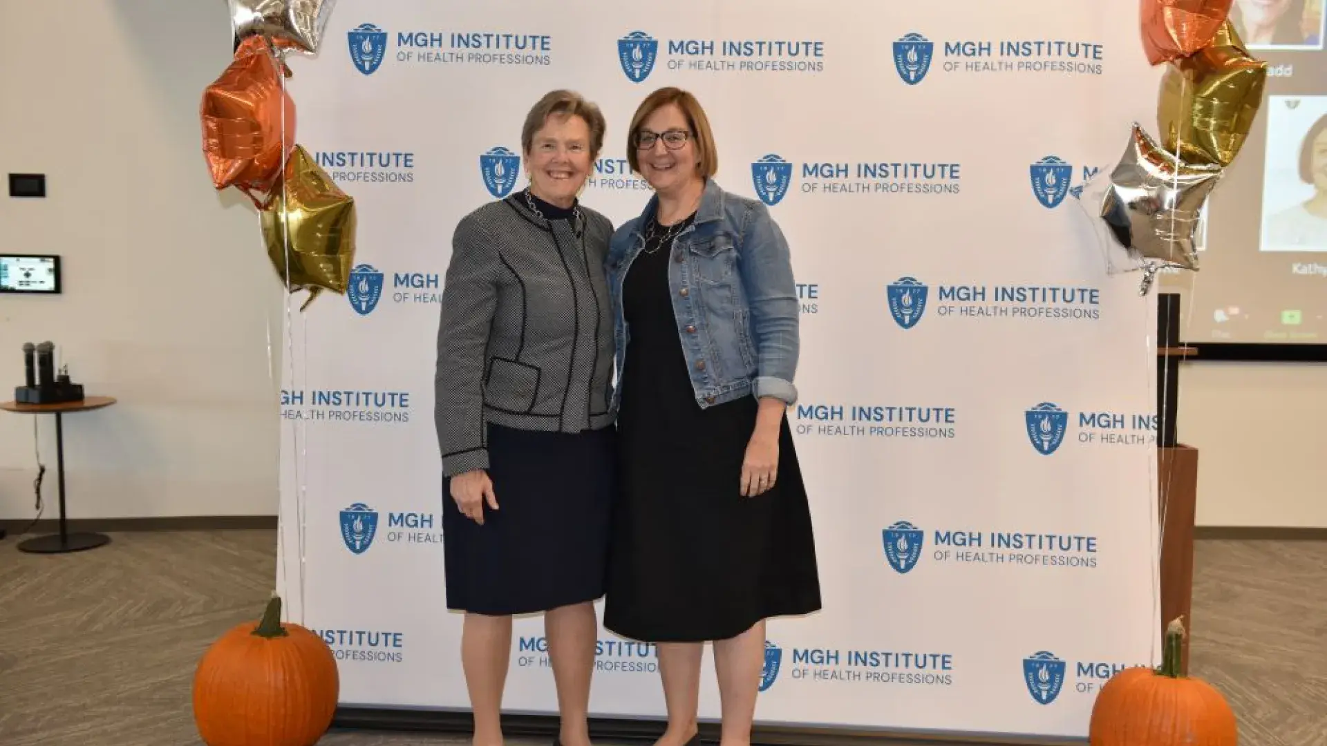 two women stand in front of MGH banner