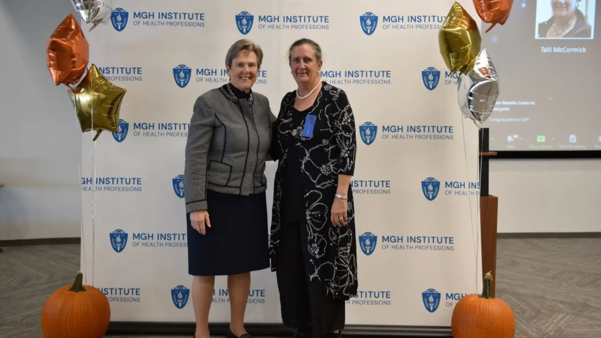 two women stand in front of MGH banner