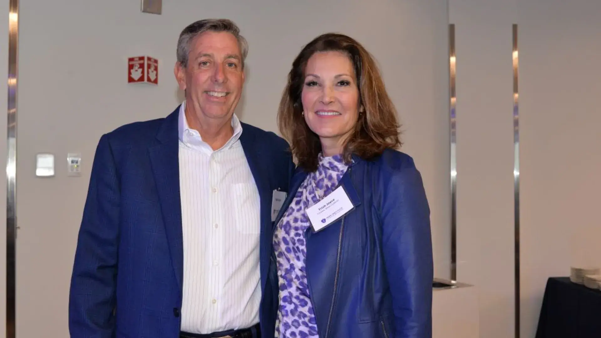 Two attendees dressed in blue at the MGH Institute of Health Professions healthcare networking event, posing for a photo.