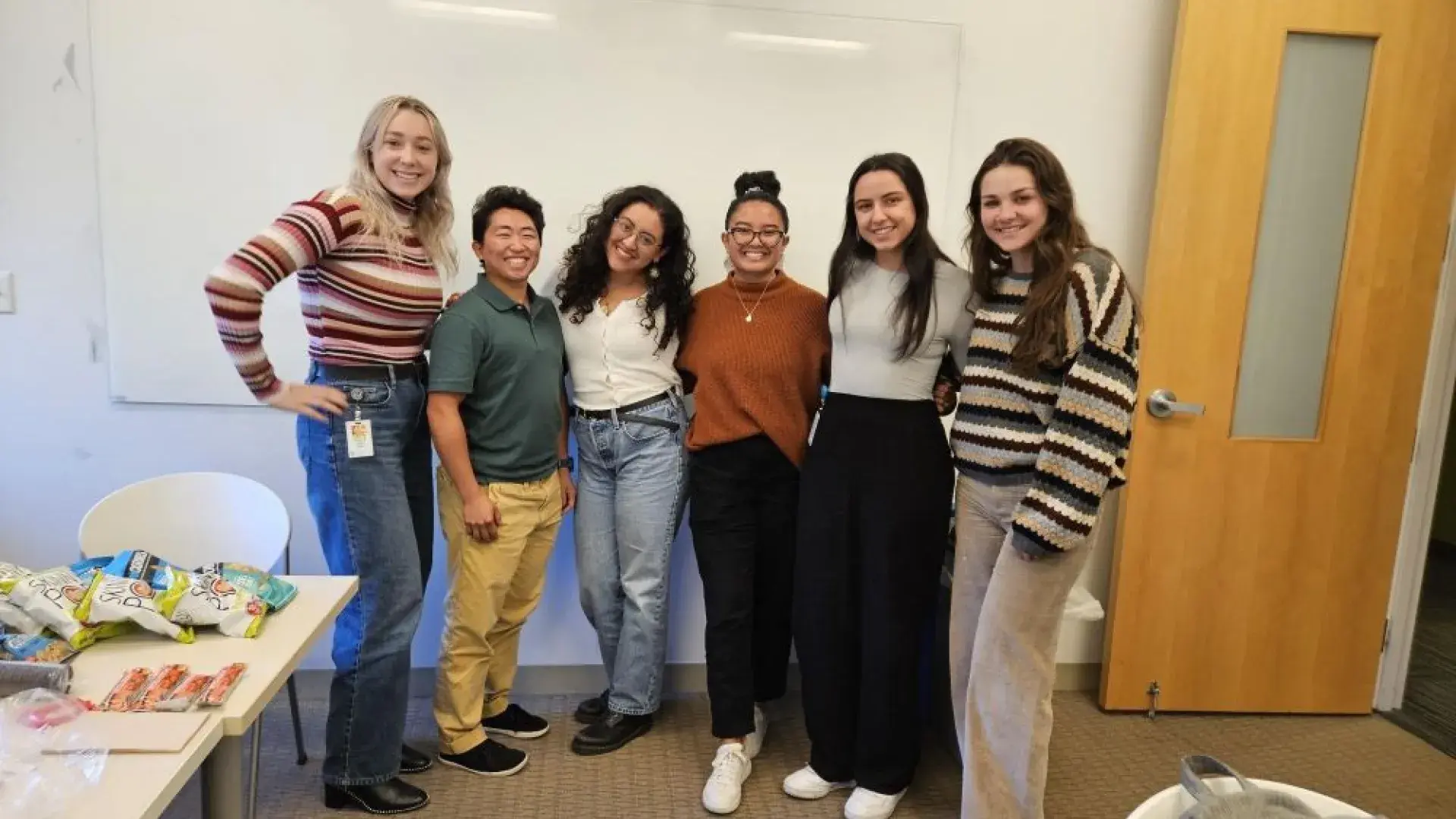 Six women pose standing next to each other