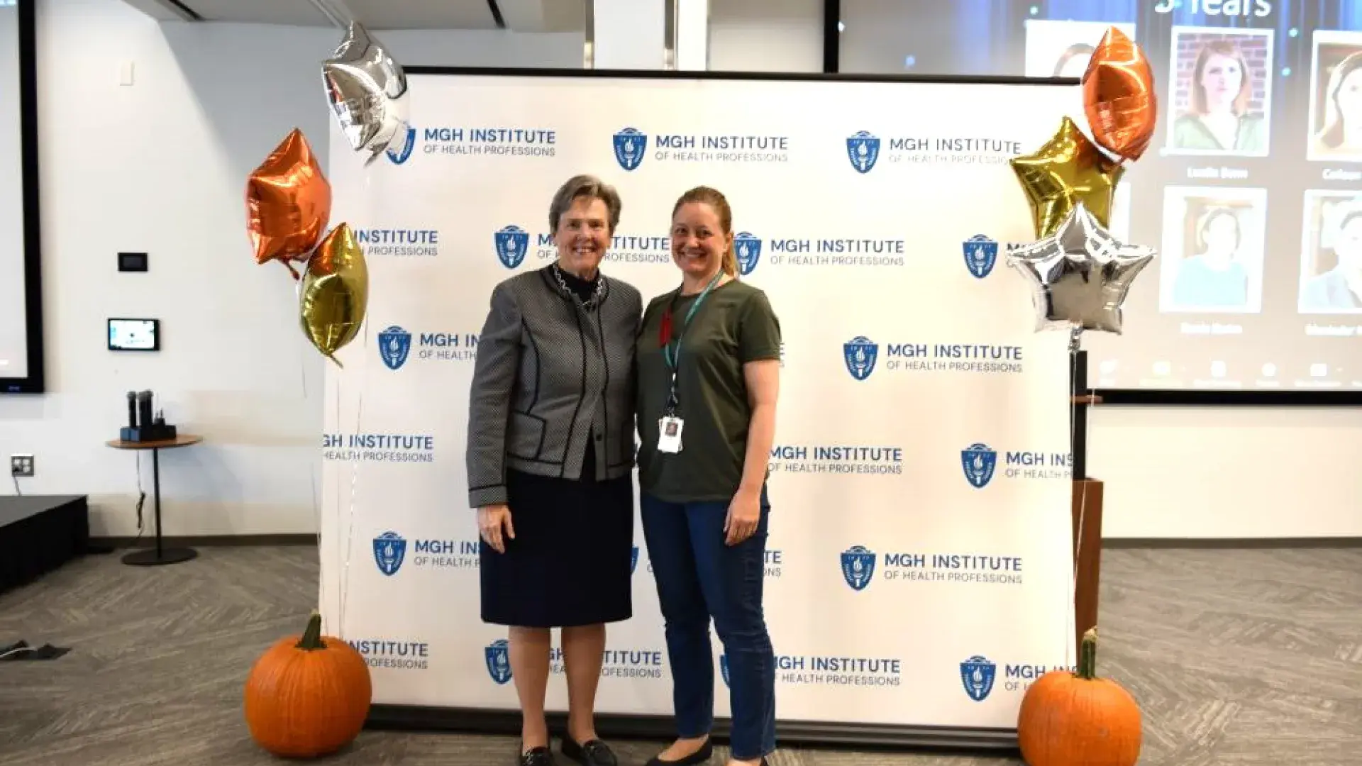 two women stand in front of back drop that says MGH institute 