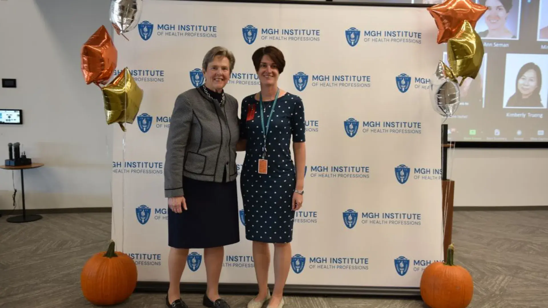two women stand in front of MGH banner