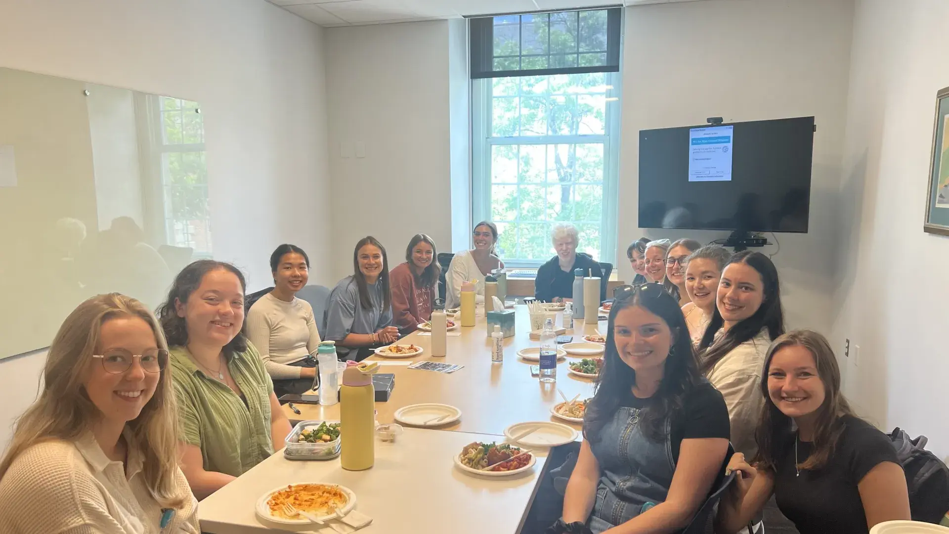 People sit at a table with food in front of them posing for the camera