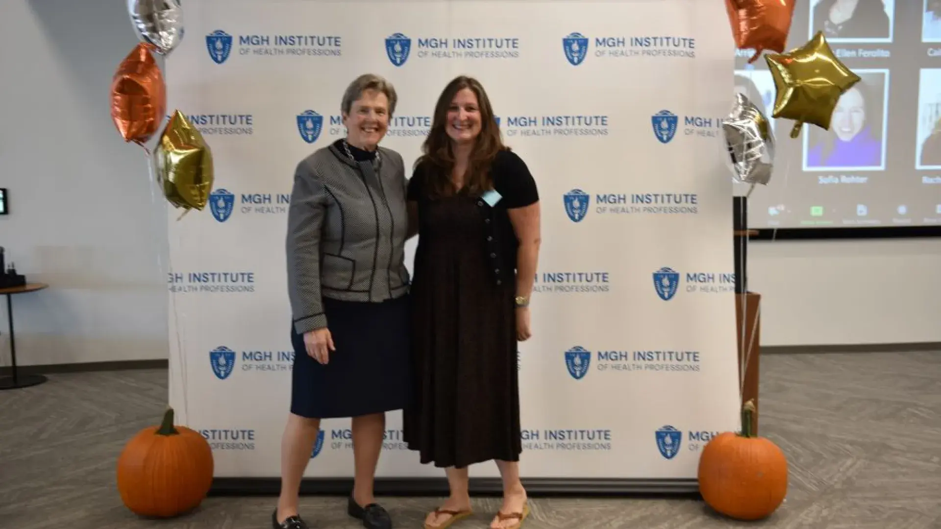 two women stand in front of MGH banner