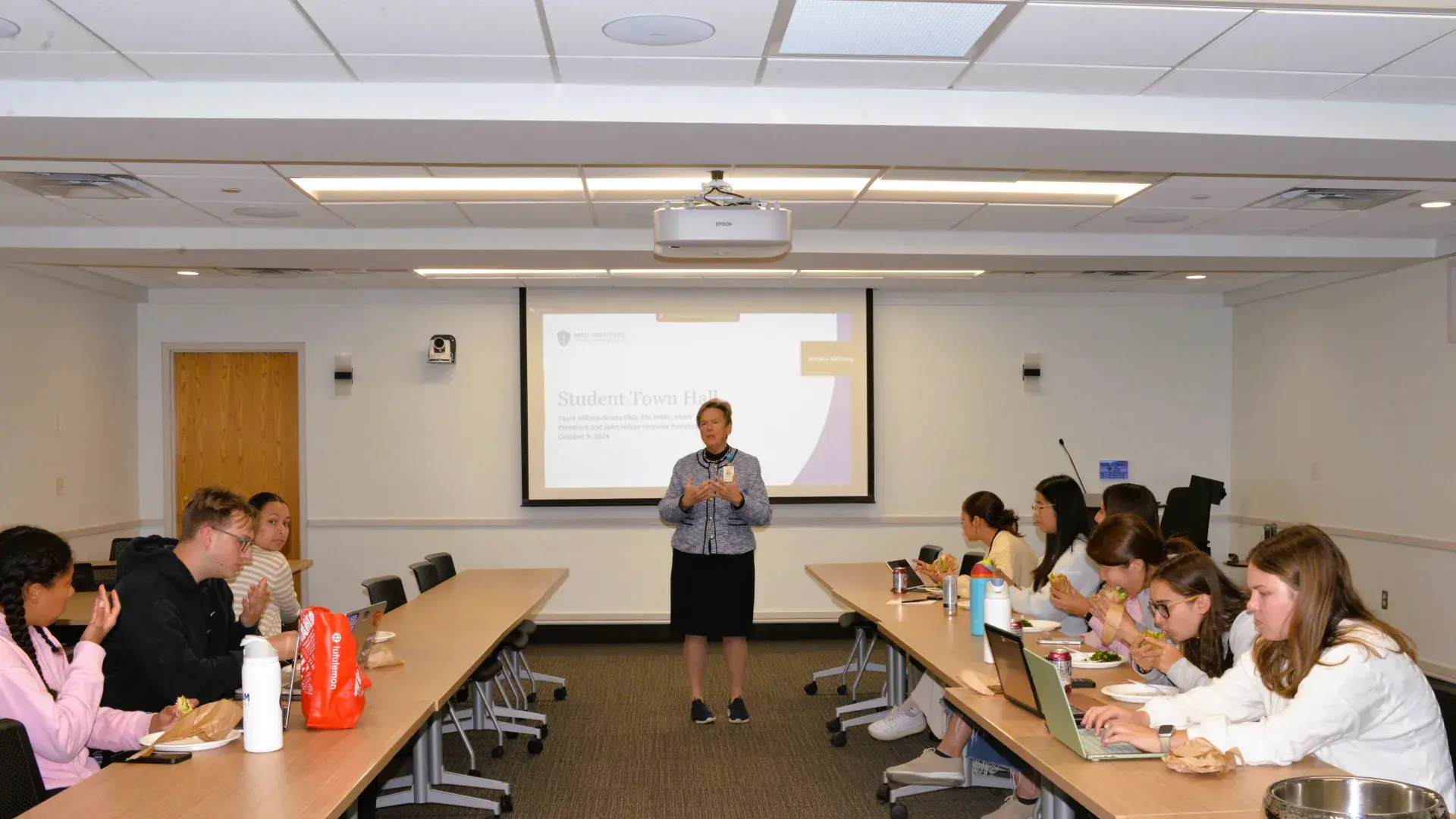 Woman standing in front of tables and students eating lunch 