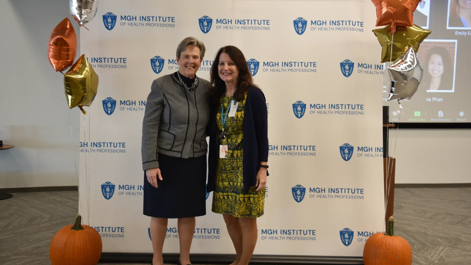 Two people stand in front of an MGH Institute backdrop
