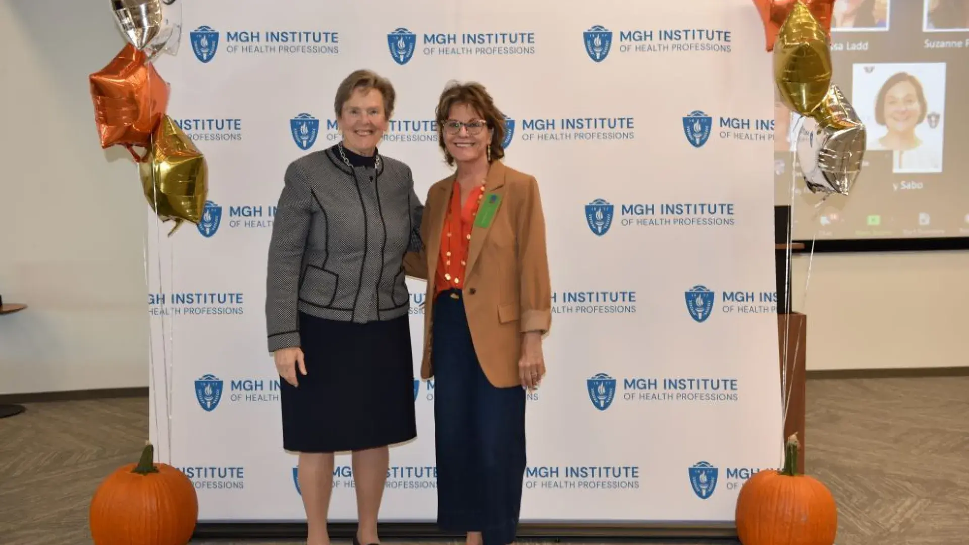 two women stand in front of MGH banner