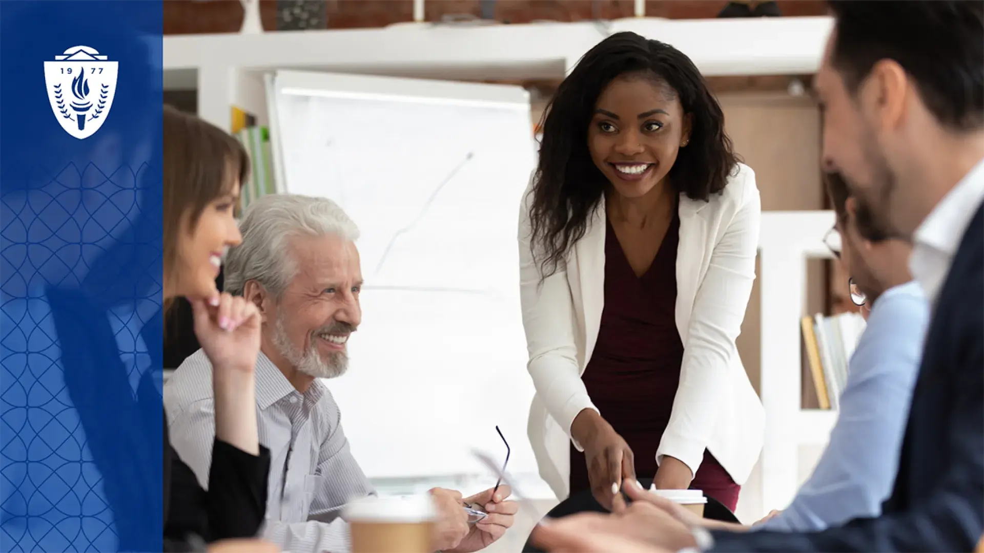 woman in white coat leading a meeting at a conference table