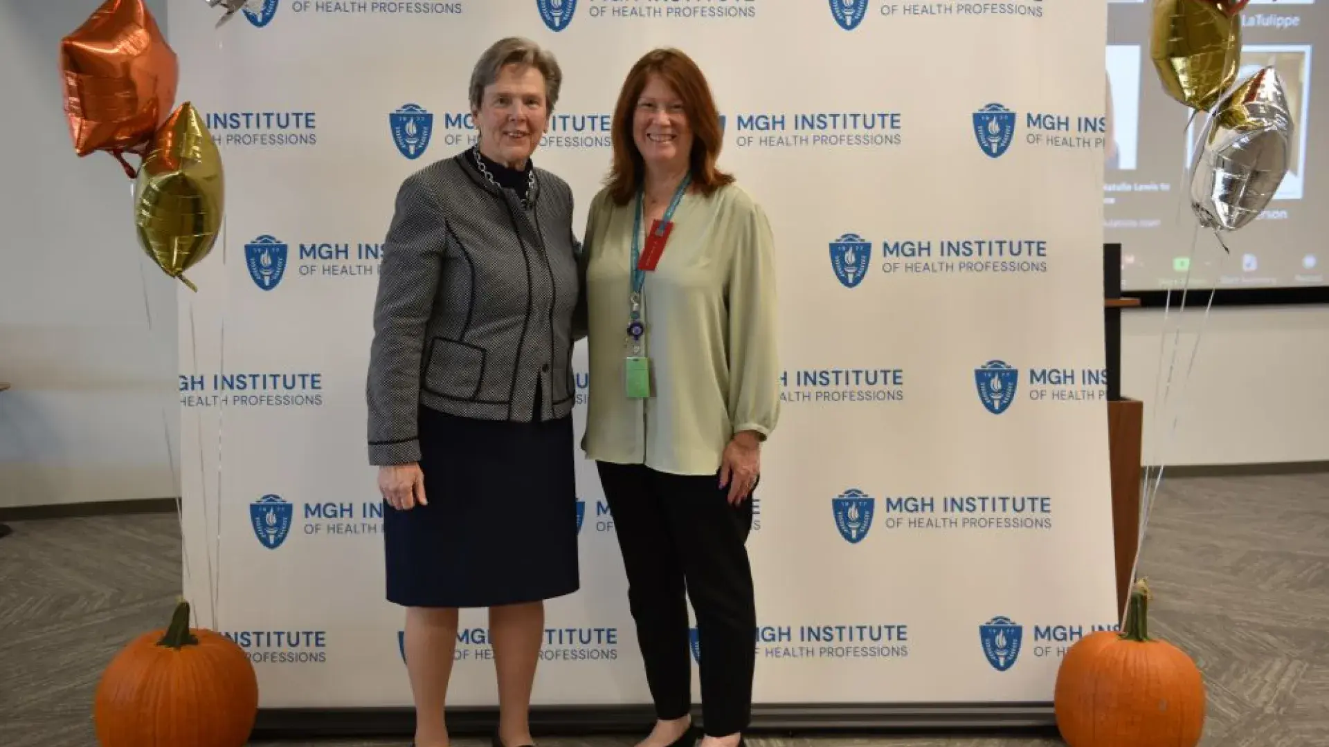 two women stand in front of MGH banner