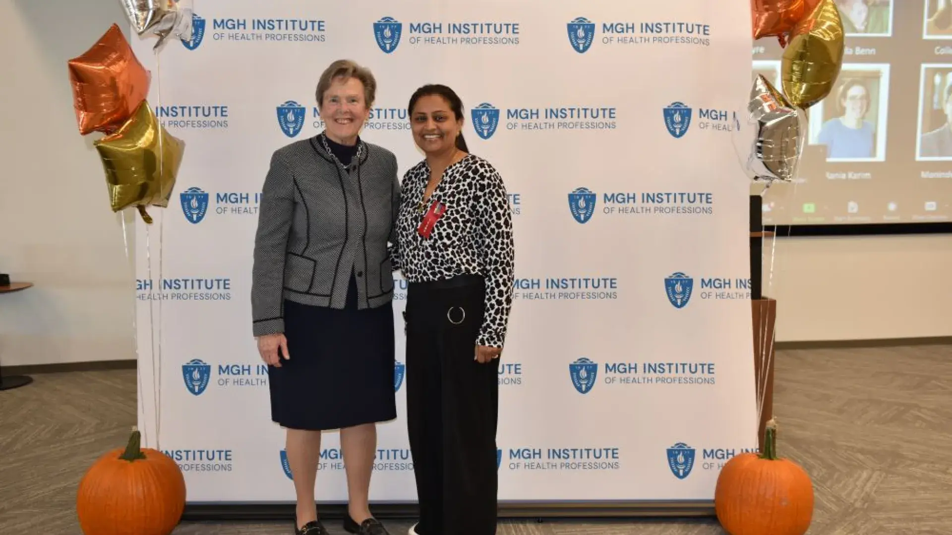 two women stand in front of MGH banner